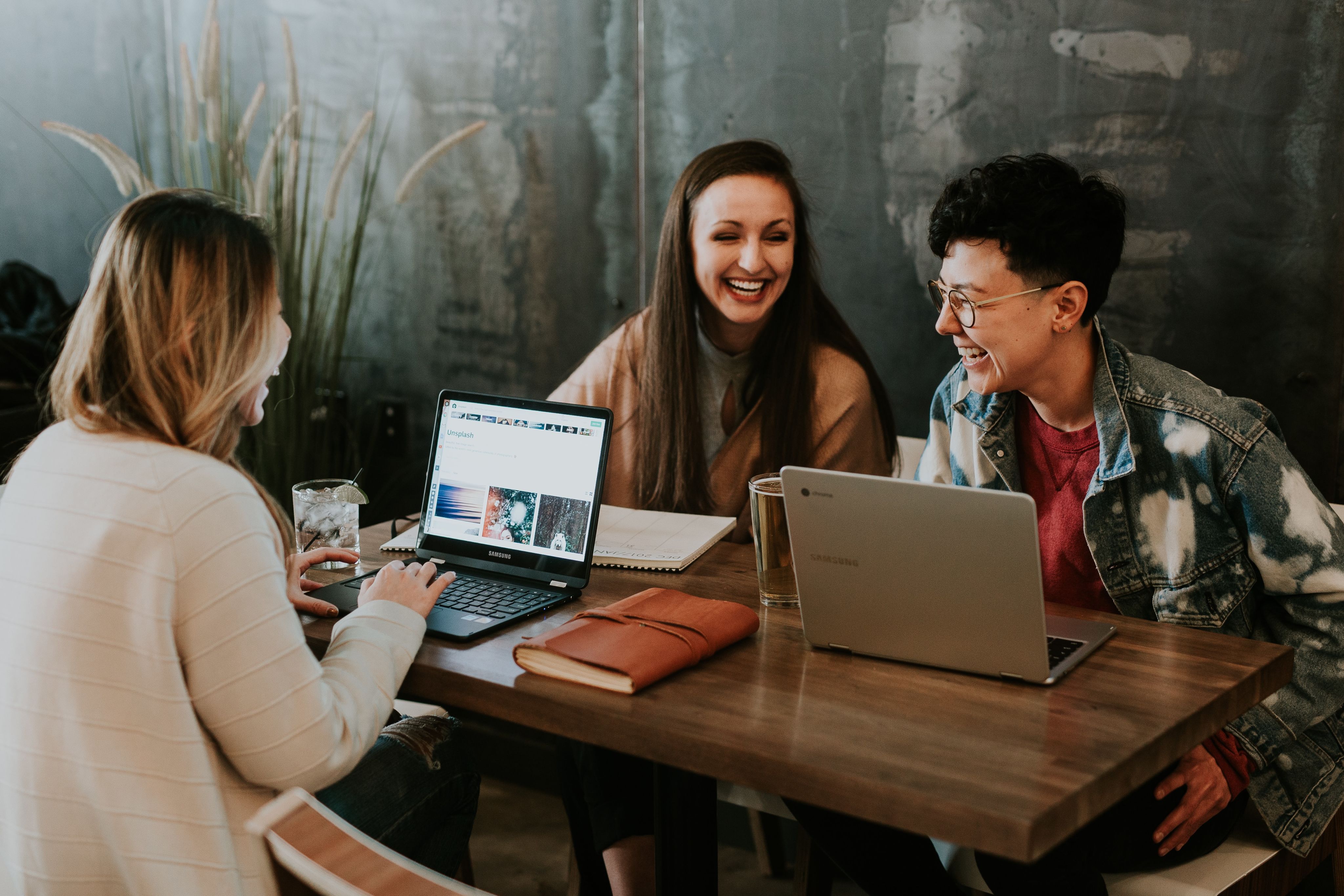three people sitting in front of table laughing together. Photo by Brooke Cagle on Unsplash