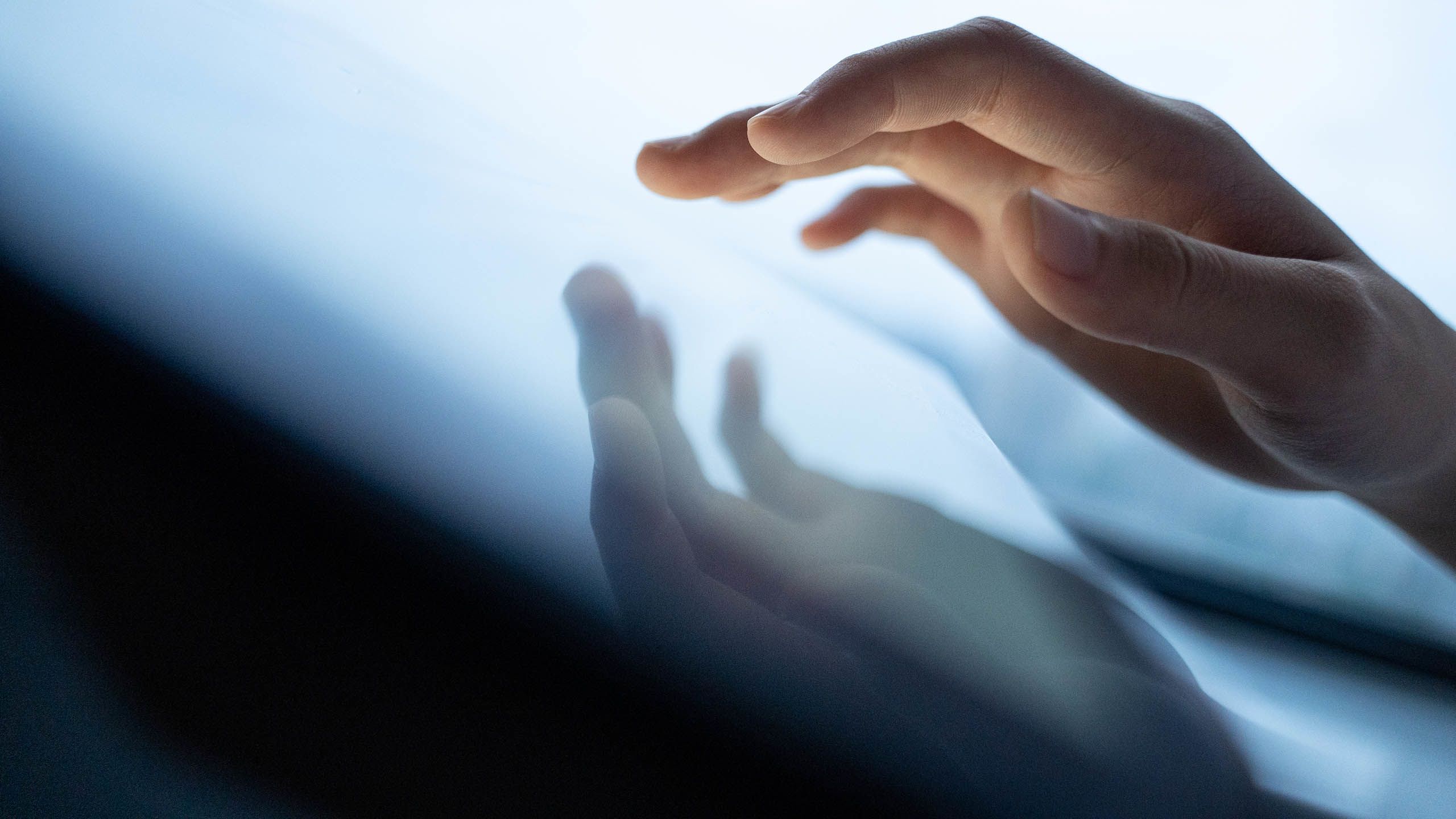 Fingers hovering over a tablet and reflected in the glass (dowell/Moment via Getty Images)