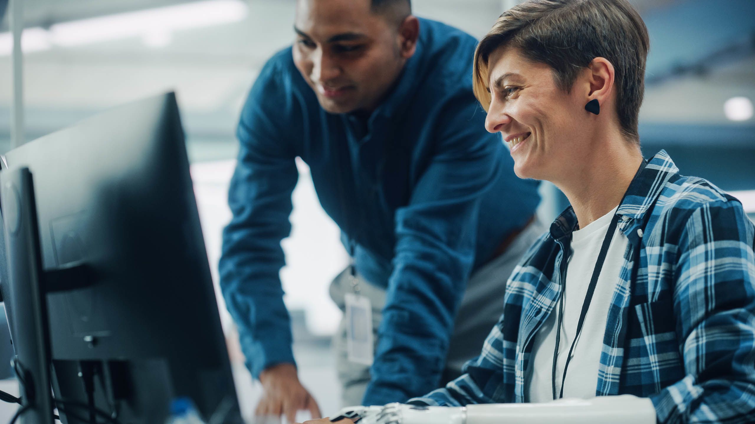 Man and woman leaning over a computer monitor (gorodenkoff/istock via Getty Images Plus)